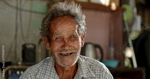 A smiling Asian man who is an elderly ragpicker or has a career collecting garbage and selling it, live in a slum village photo