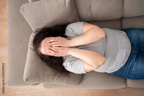 Top view of sad woman complaining in the night lying on a couch in the living room at home