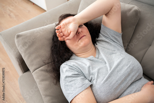 Peaceful woman lying on back on comfortable couch at home, covering eyes with hand, sleeping at daytime, feeling tired, enjoying relaxation, leisure, break, weekend.