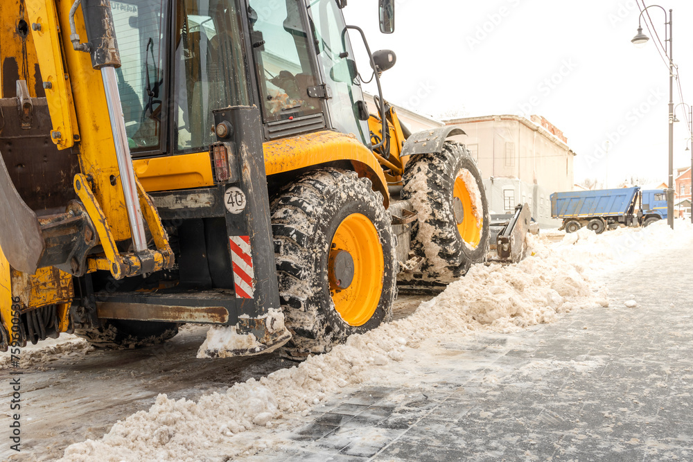 Cleaning city streets, a tractor-loader loads dirty snow into a dump truck. removal of snow and ice after heavy snowfalls and blizzards. Outdoor snow blower, sidewalk and driveway cleaning. Cleaning city streets, a tractor-loader loads dirty snow into a dump truck. removal of snow and ice after heavy snowfalls and blizzards. Outdoor snow blower, sidewalk and driveway cleaning.