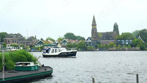 Embarcación navegando por el río Zaan al fondo la población de Zaandijk (Nederland) photo