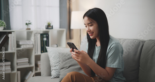 Selective focus ,Happy young woman sitting on sofa enjoy using mobile phone for online shopping cashless in living room at home © Johnstocker