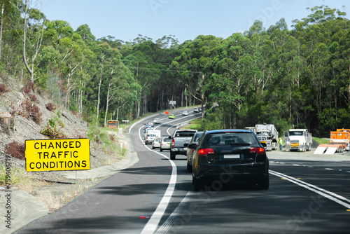 Changed traffic conditions sign and long line of cars backed up at roadwork site on highway