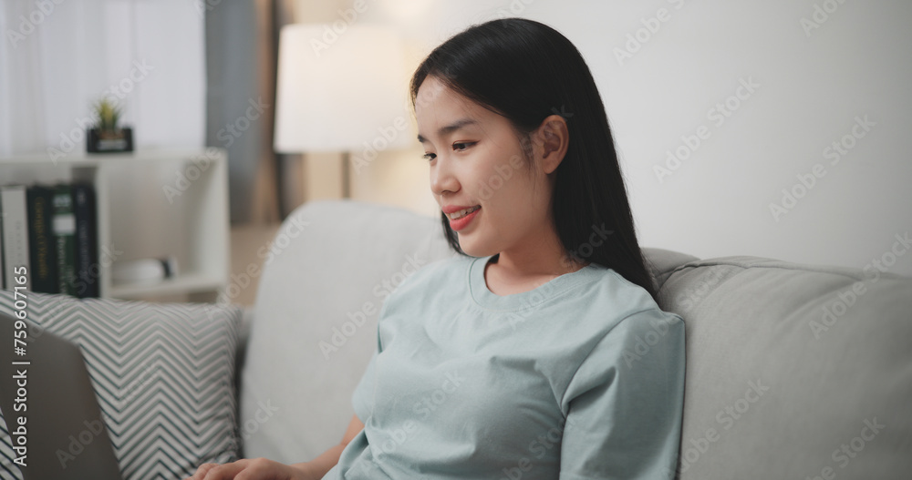 Selective focus, Relaxed young woman sitting on sofa using laptop for online shopping cashless in living room at home ,Internet Connectivity and Online Concept. Selective focus, Relaxed young woman sitting on sofa using laptop for online shopping cashless in living room at home ,Internet Connectivity and Online Concept.