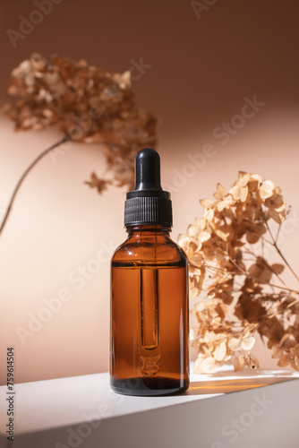 Dropper bottle on podium with dry flowers on pastel beige background. Aesthetic, minimal beauty product packaging design.