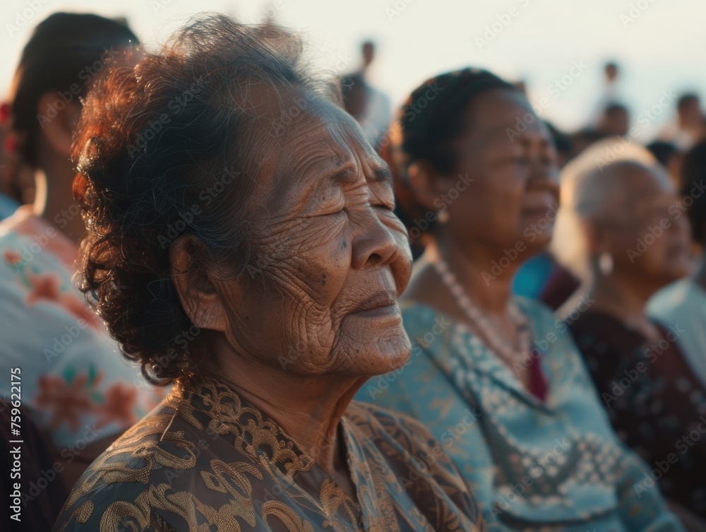 A close-up shot of a group of women dressed in Buddhist attire, sitting peacefully next to each other in meditation A close-up shot of a group of women dressed in Buddhist attire, sitting peacefully next to each other in meditation