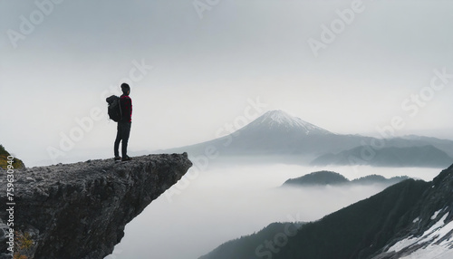 バックパックを背負って崖の端に立って壮大な景色を眺めている男性