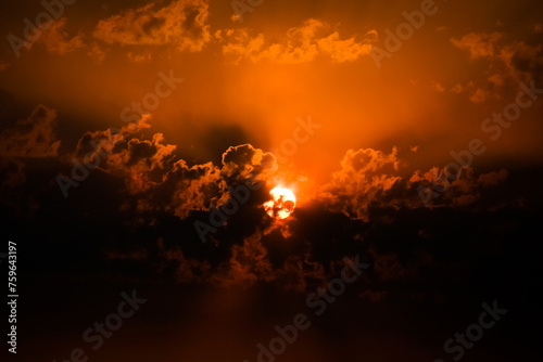 the sun rising through the clouds