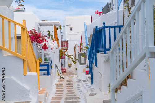 Fototapeta Naklejka Na Ścianę i Meble -  narrow side street with traditional whitewashed walls and blue accents in Mykanos Greece. traditional windmill on the sea shore and colorful restaurants