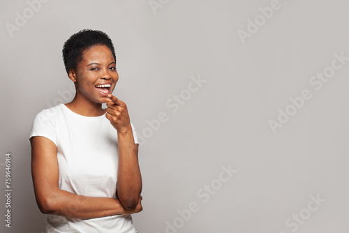 Happy woman pointing at camera and having fun on gray studio wall background © millaf