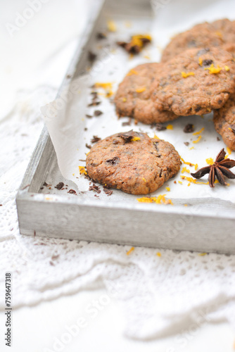 home made chocolate cookies with orange zest, chocolate chips and spices perfect for christmas on grey wooden background close up selective focus