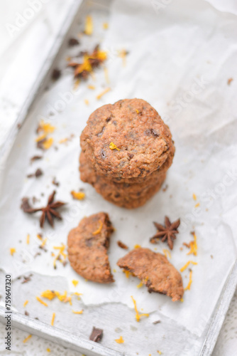 home made chocolate cookies with orange zest, chocolate chips and spices perfect for christmas on grey wooden background close up selective focus