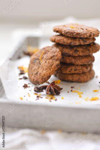home made chocolate cookies with orange zest, chocolate chips and spices perfect for christmas on grey wooden background close up selective focus