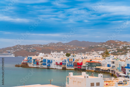 narrow side street with traditional whitewashed walls and blue accents in Mykanos Greece. traditional windmill on the sea shore and colorful restaurants photo