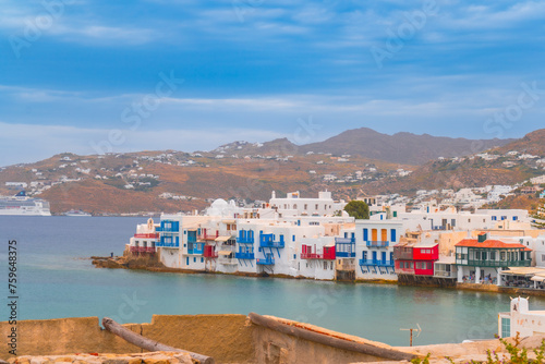 narrow side street with traditional whitewashed walls and blue accents in Mykanos Greece. traditional windmill on the sea shore and colorful restaurants photo