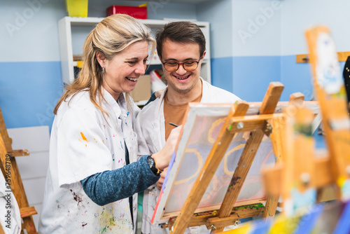 Fotografi Caring art teacher guides her student with Down syndrome.