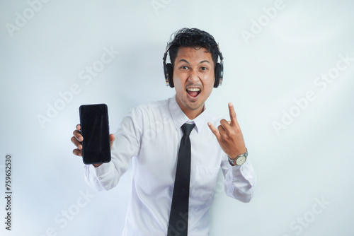 Asian man enjoying music from mobile phone using wireless headset isolated on white photo