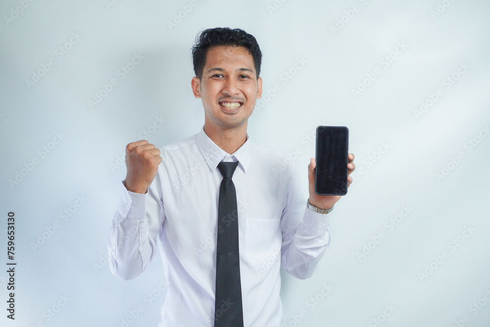 Adult Asian man clenched fist with excited expression while showing blank mobile phone screen Adult Asian man clenched fist with excited expression while showing blank mobile phone screen