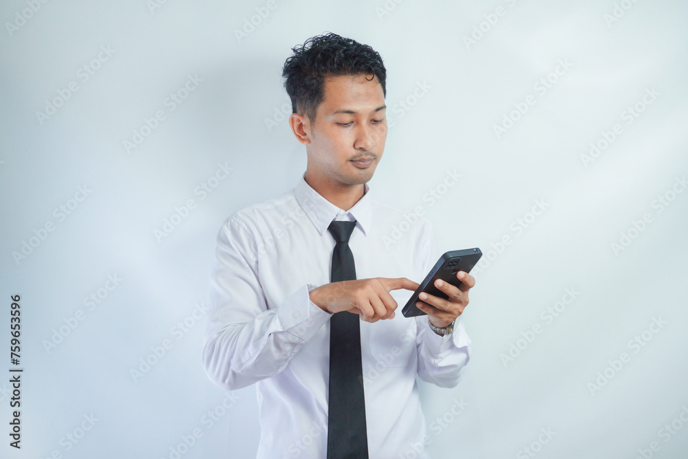 Adult Asian man pointing to mobile phone that he hold with wow expression Adult Asian man pointing to mobile phone that he hold with wow expression