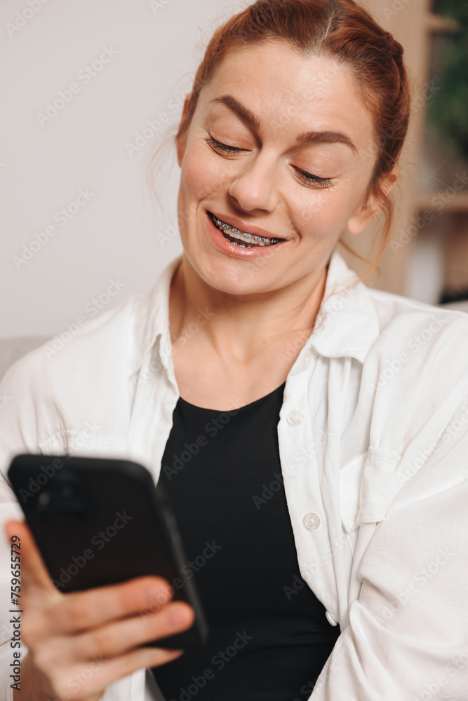 Portrait of mature smiling woman with braces using smart phone at home Portrait of mature smiling woman with braces using smart phone at home