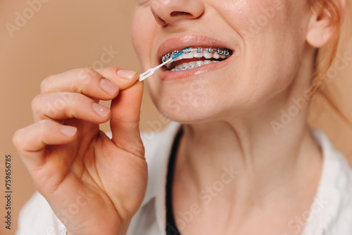 Close-up Unrecognizable woman cleans braces with a brush on beige background