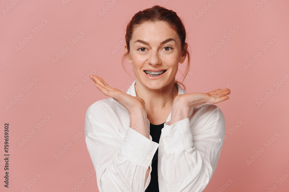Modern happy woman showing smile with braces on pink background Modern happy woman showing smile with braces on pink background