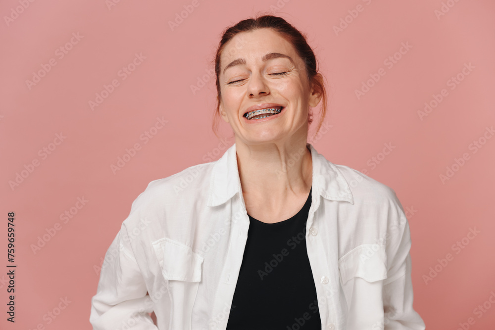Modern happy woman smiling widely with braces on pink background Modern happy woman smiling widely with braces on pink background