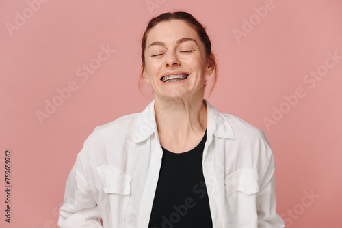 Modern happy woman smiling widely with braces on pink background
