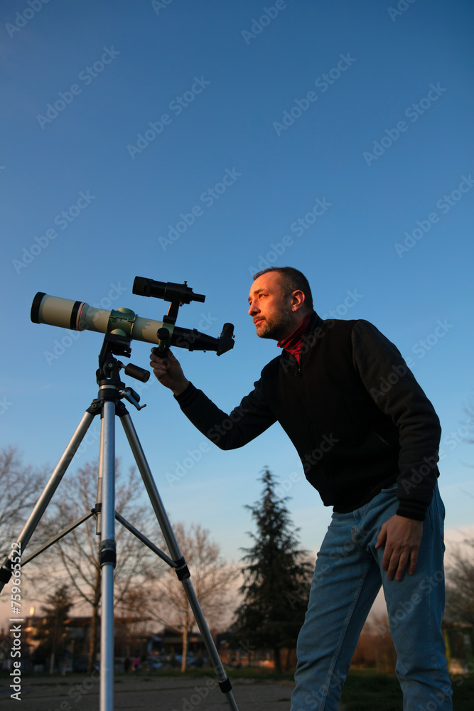 Amateur astronomer observing Sun eclipse and Sun with a telescope and special solar filter.