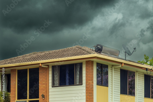 Rain and storm clouds and suburban house with solar hot water heater. photo