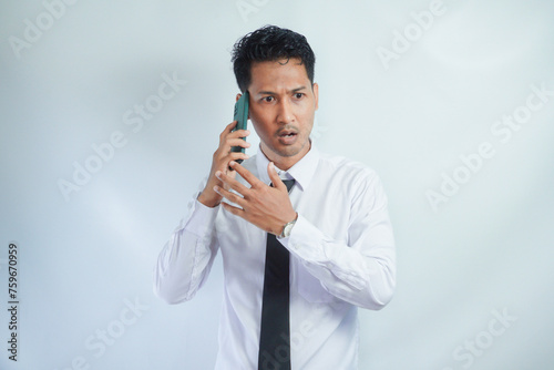 Adult Asian man showing not happy expression when answering a phone call photo