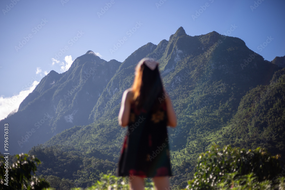 selective focus on big green mountains with beautiful shapes Doi Luang Chiang Dao is a conservation area for animals. The blurry foreground is a young Asian woman standing looking at the