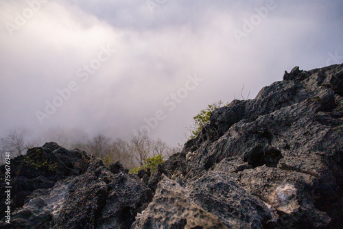 Selective focus  tall gray rocky mountains with beautiful natural rock patterns leading to the highest point  a mist on the mountain.