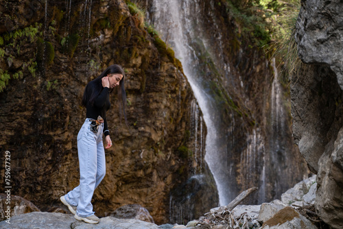 A woman explores new, fantastic places around the world. Female hiker crossing the waterfall.