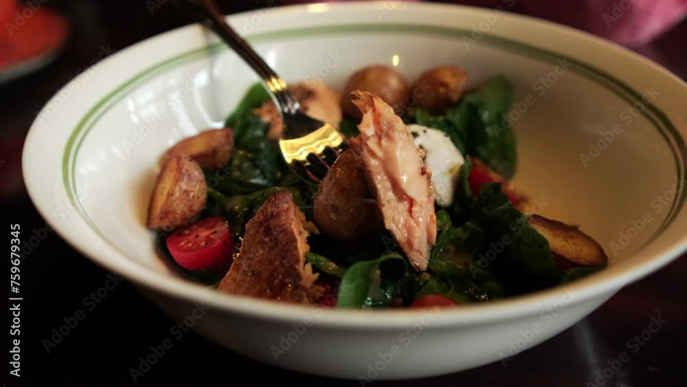 A savory salad with smoked salmon, potatoes, cherry tomatoes, spinach, and a poached egg served in a white bowl.