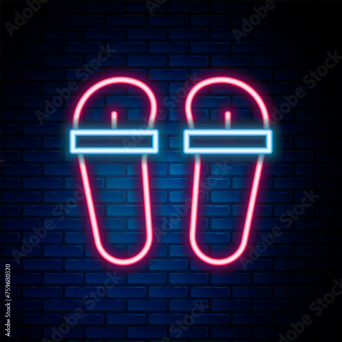 Glowing neon line Flip flops icon isolated on brick wall background. Beach slippers sign. Colorful outline concept. Vector
