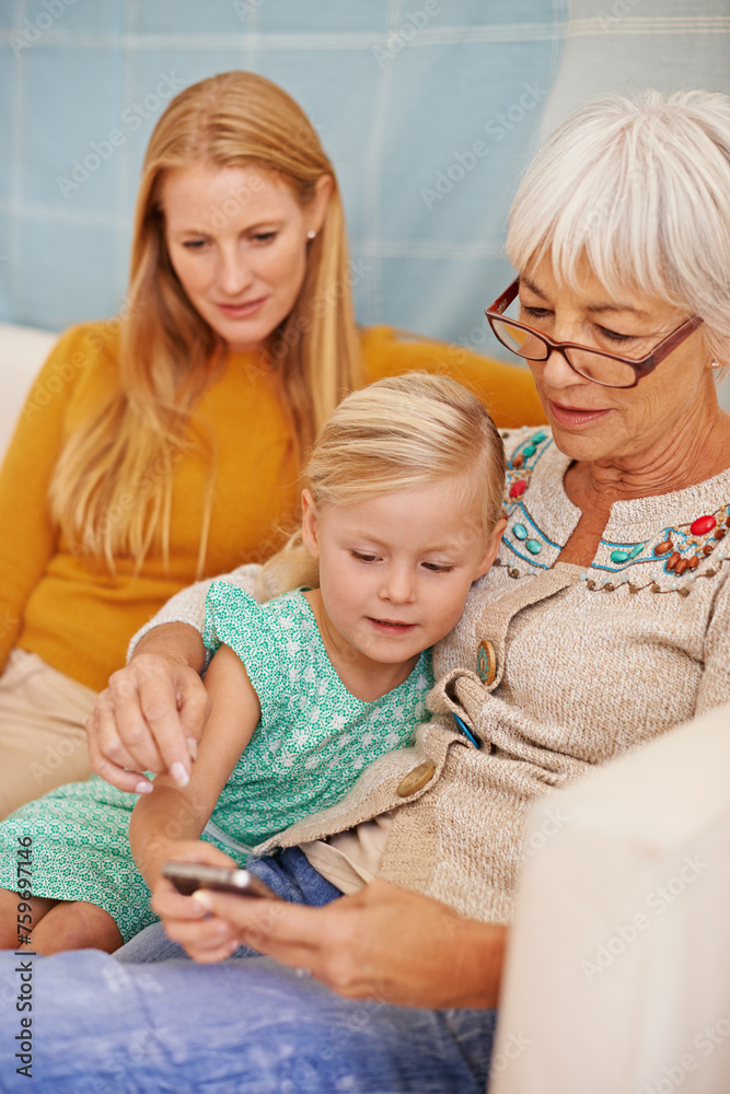Girl, phone and social media at a home with grandmother, family and mother together with game. Learning, online and senior woman with child and mom with love, support and care in a house with tech Girl, phone and social media at a home with grandmother, family and mother together with game. Learning, online and senior woman with child and mom with love, support and care in a house with tech