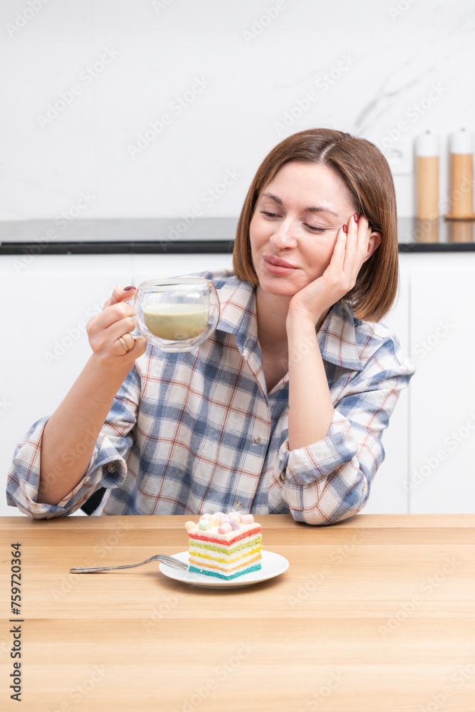 Close-up portrait of attractive girl drinking hot matcha tea and eating tasty cake in the kitchen Close-up portrait of attractive girl drinking hot matcha tea and eating tasty cake in the kitchen