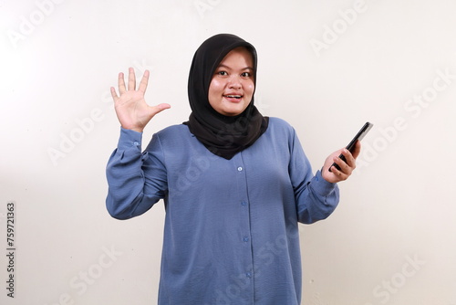 Wow excited asian adult woman standing holding a cell phone while showing five fingers