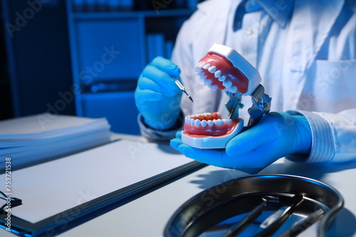An oral surgeon is using a specialized dental instrument to inspect the mouth of a denture as he practices treating a patient, Denture is being examined by dentists for use in practicing their skills. photo