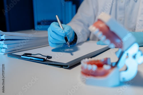 The dentist is taking notes summarizing all of the patient's treatments for the day, An oral specialist sits in his private office while writing a treatment plan.