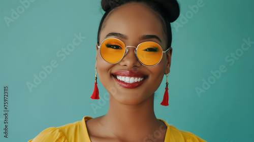 Close up shot of stylish young woman in sunglasses smiling against teal color background. Beautiful female model with copy space.professional photography