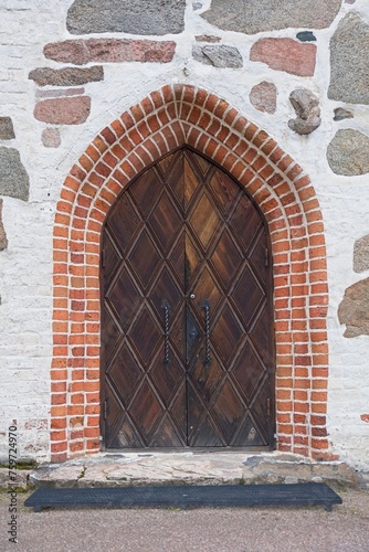 Decorative wood door with red brick arch on stone building. © Raimo