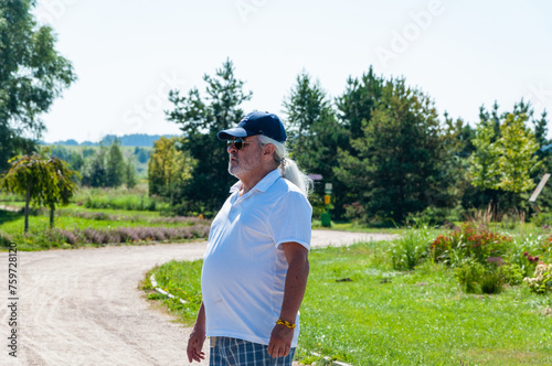 Hispanic man old senior grandfather in summer style Cuban cap outdoor in spring park got lost