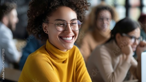 Cheerful female student has fun during break in colleague, laughes at jokes of groupmates, keeps hands crossed, wears round optical glasses and yellow turtleneck sweater. Positive emotions concept