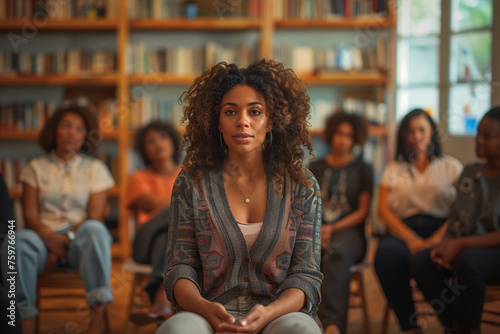 A psychologist leading a workshop on coping strategies for depression and anxiety. A group of women are sitting in circle during a therapy meeting led by and african woman to help others manage stress © ivlianna