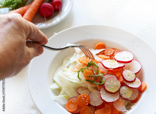 Insalata di finocchi con carote, ravanelli e semi di sesamo in un piatto su sfondo bianco. Concetto di cibo vegetariano e salutare. Copia spazio. Vista dall'alto. photo