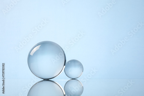 Transparent glass balls on mirror surface against light background. Space for text © New Africa