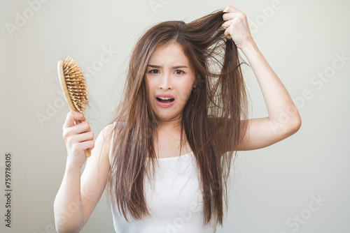 Damaged hair, amazed asian young woman, girl hand holding brush comb, hairbrush with fall hair from scalp after brushing, face worry about balding. Health care, beauty treatment, hair loss problem.