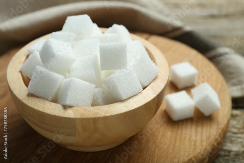 White sugar cubes in bowl on wooden board, closeup